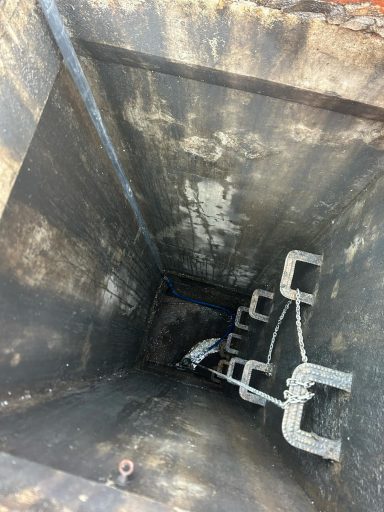 Vertical view down a dark, industrial shaft with metal supports and cables.